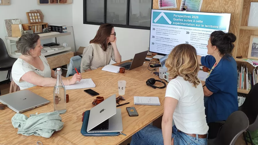 Quatre personnes travaillent autour d'une table et regardent une présentation sur les perspectives 2026